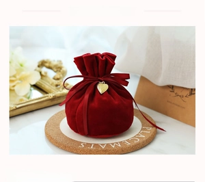 Macro shot of red velvet candy gift bag featuring a golden heart pendant and ribbon tie