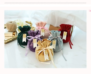 Detail of velvet wedding favor bags with gold thank you tags in assorted colors