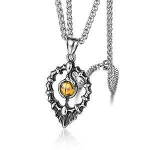Detail of silver snake pendant with heart-shaped hollow design and yellow gemstone inlay