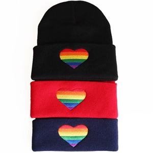 Close-up of rainbow heart embroidery on multi-color knitted beanie hats with detailed texture