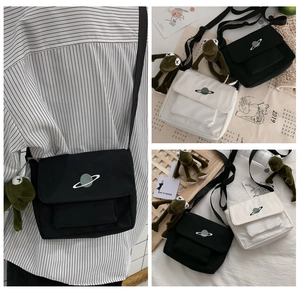 Detail of canvas crossbody bag with planet embroidery and iconic frog plush charm