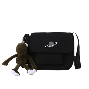 Large black canvas messenger bag with planet embroidery and plush monkey charm accessory