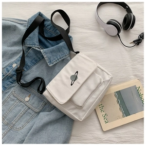 Detailed view of beige canvas tote bag with planet embroidery and adjustable black strap