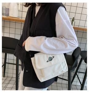 Close-up of white canvas crossbody bag featuring delicate planet embroidery in a cafe setting