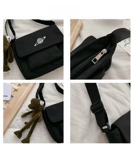 Detail view of black canvas crossbody bag featuring planet embroidery and frog charm