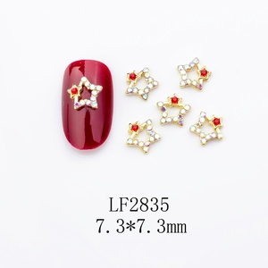 Close-up of golden star nail art charm with AB rhinestones and red gem, size 7.3mm