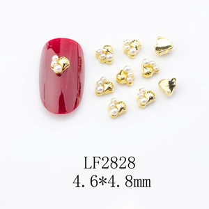 Detail of 4.6x4.8mm gold alloy nail art charm with pearls on a red nail sample