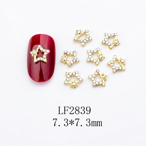 Close-up of gold star nail charms with iridescent rhinestones on white background