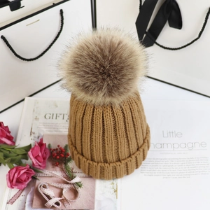Detail der camelfarbenen Strickmütze mit großem Kunstfell-Bommel in Geschenkoptik