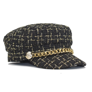 Close-up of black tweed newsboy hat featuring metallic gold thread and metal chain detail