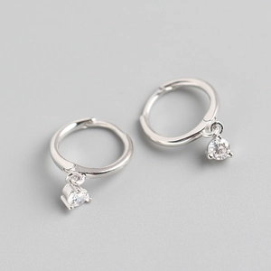 Detail of silver S925 huggie earrings featuring small hanging clear zircon stones
