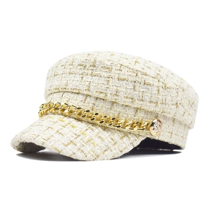Detail of white tweed baker boy hat featuring gold metallic chain and lion buttons