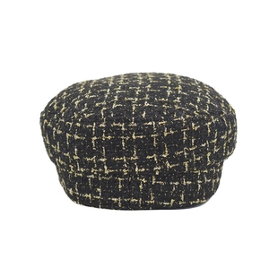 Close-up of vintage black and gold tweed wool beret with intricate woven metallic threads