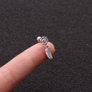 Macro view of silver stainless steel dreamcatcher ear stud with feather pendant on finger