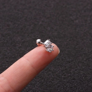 Close-up of small silver flower stud earring with zircons held on a fingertip