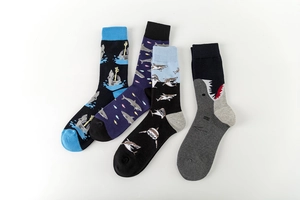 Detail view of four shark pattern crew socks in assorted blue, purple, and grey colors