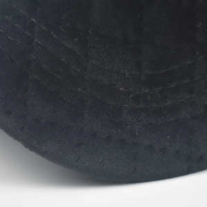 Detailed macro view of black corduroy baseball cap with quilted diamond pattern stitching