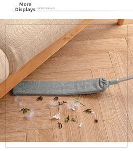 Detailed view of the slim crevice duster cleaning dust and hair under the sofa on wood floors