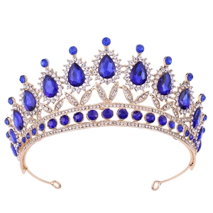 Detailed close-up of a golden baroque tiara with blue teardrop crystals and white rhinestones