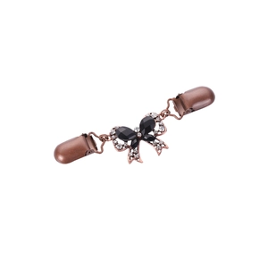 Dettaglio della clip per cardigan in bronzo con fiocco in pietra nera e strass
