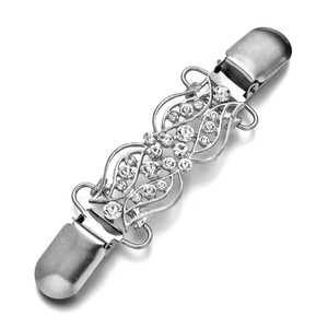 Dettaglio di un fermaglio per cardigan in argento con motivo floreale e strass brillanti