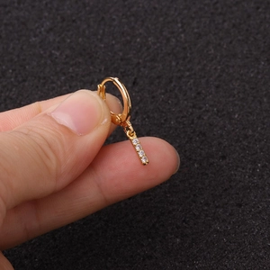 Détail d'une boucle d'oreille dorée avec pendentif en lettre et pierres de zircone