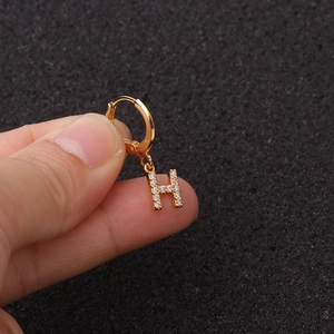Gros plan d'une manchette d'oreille dorée avec pendentif lettre H serti de zircon