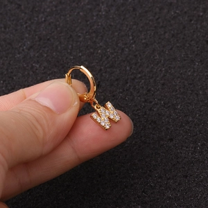Détail d'une boucle d'oreille lettre W dorée avec des pierres de zircon étincelantes