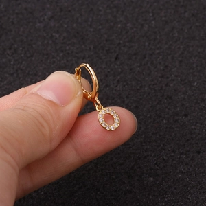 Gros plan de la boucle d'oreille lettre O dorée sertie de zircons pour le cartilage