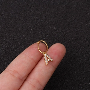 Gros plan d'une boucle d'oreille dorée lettre A ornée de pierres de zircone cubique