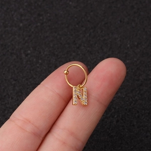 Détail d'une boucle d'oreille lettre N dorée avec pierres zircon sur le lobe