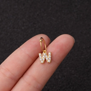 Vue macro détaillée de la boucle d'oreille créole en acier doré avec pendentif lettre W serti