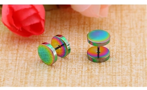 Macro view of iridescent rainbow barbell stud earrings on a textured floral background