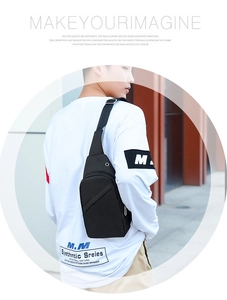 Detail of black crossbody chest bag with adjustable strap and headphone jack on urban background