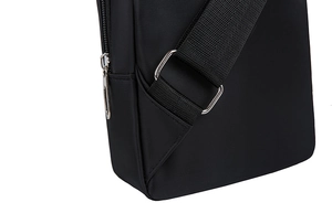 Close-up of black nylon fabric texture, reinforced strap joint and metal zipper on chest bag