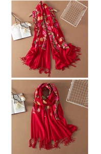 Close-up of red cashmere wool shawl featuring intricate floral embroidery and tassel fringe