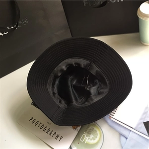 Classic black wide brim cotton bucket hat with internal lining detail on a white surface