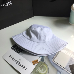 Detailed texture of white cotton bucket hat placed on a magazine with lifestyle accessories