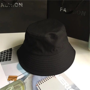 Minimalist wide brim black cotton bucket hat for men and women on fashion tabletop