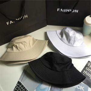 Flat lay of wide brim cotton bucket hats in black, white and khaki on a fashion set