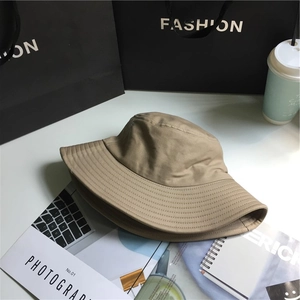 Detail of khaki wide brim bucket hat with stitching on a white desk with lifestyle props