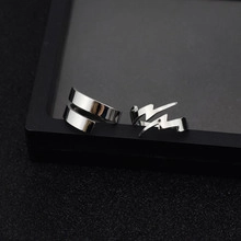 Close-up of silver lightning bolt and wide band open rings on a black textured surface