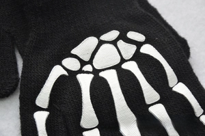 Detail of warm black knitted gloves with high-quality glowing skeleton bone print