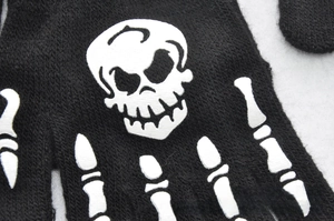 Macro detail of knit winter gloves featuring glow-in-the-dark skull and bone patterns