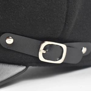 Detailed close-up of wool texture and leather strap with silver buckle on black navy hat