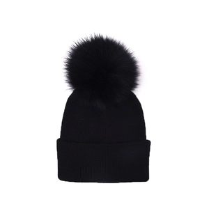 Detail view of black knit winter hat with large faux fur pom-pom and thick folded brim