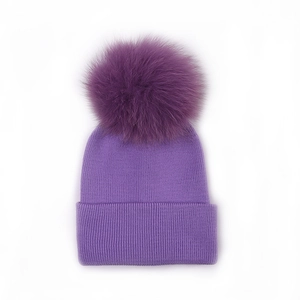 Detailed close-up of purple knit baby beanie featuring a large fluffy faux fur pompom