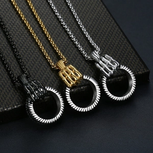 Close-up of skeleton hand pendants holding a ring in black, gold, and silver finishes