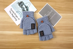 Detail of light blue knitted fingerless gloves with a flip top cover and wooden button