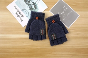 Detail of dark blue knitted convertible mittens with orange buttons on wood background